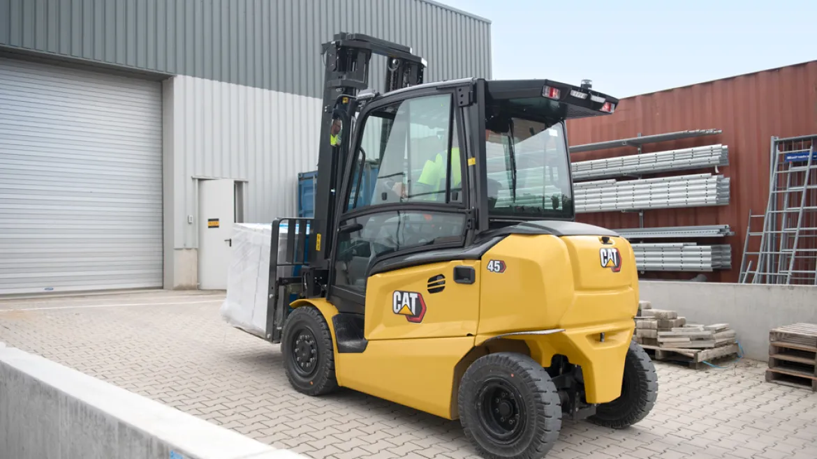 Cat electric counterbalance forklift carrying a load outside a warehouse