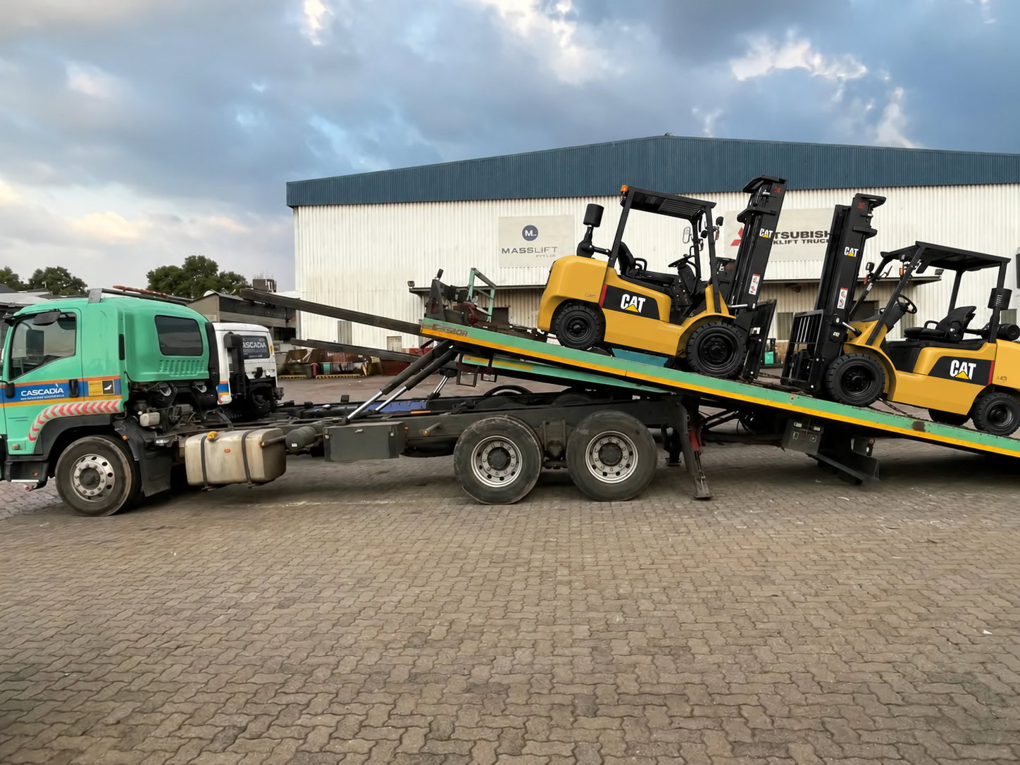 Two Cat forklifts loaded on a tilted flatbed truck at the Masslift Africa depot